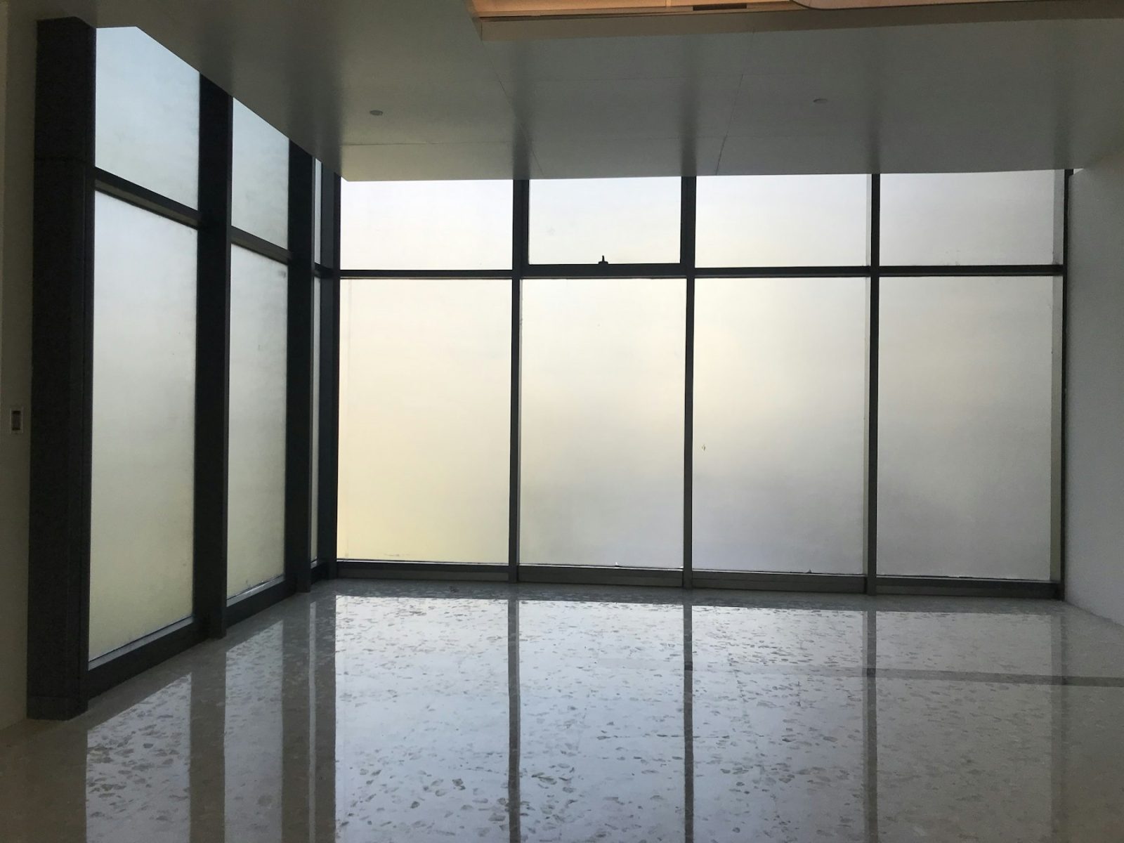 Raum mit raumhohen Fenstern, die mit satinierter Glasdekorfolie beklebt sind – das Licht fällt gedämpft herein