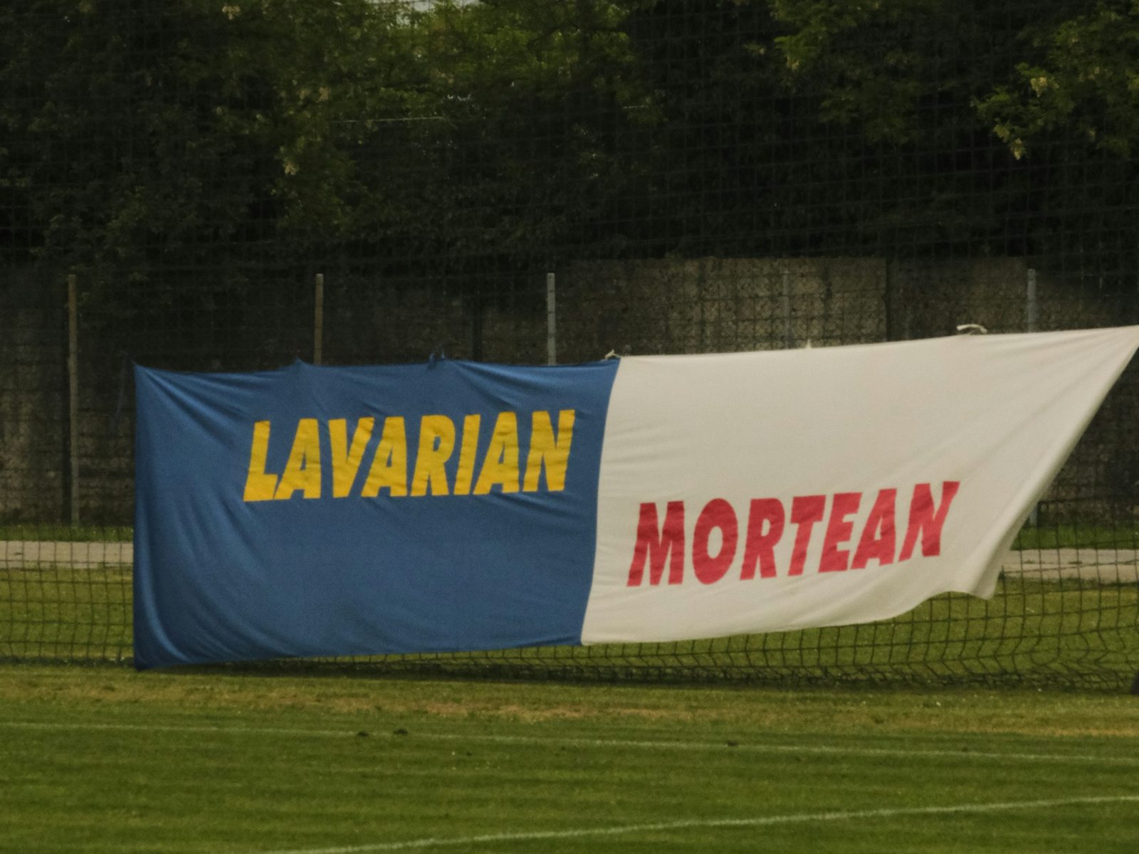 Zweifarbiges Stoffbanner an einem Ballfangzaun am Spielfeldrand