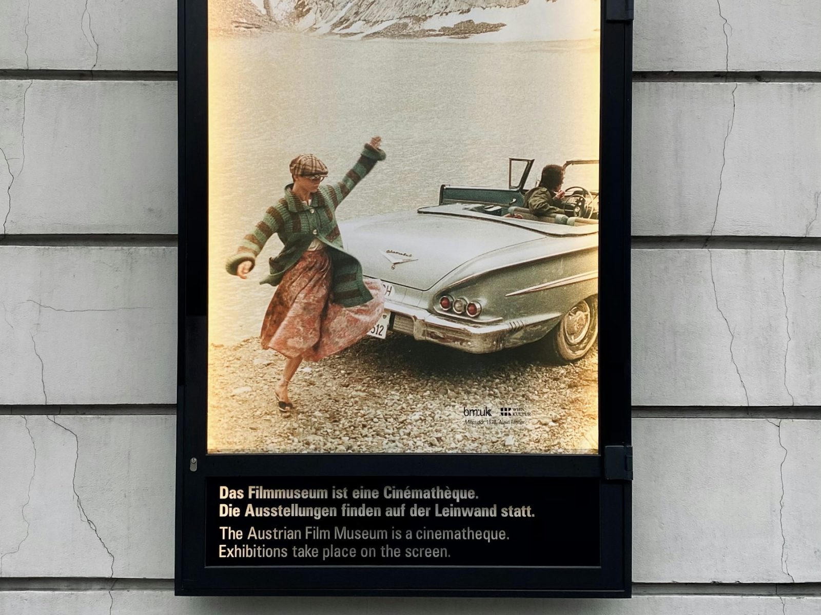 Plakat hinter Glas in einem Schaukasten an einer Hausfassade