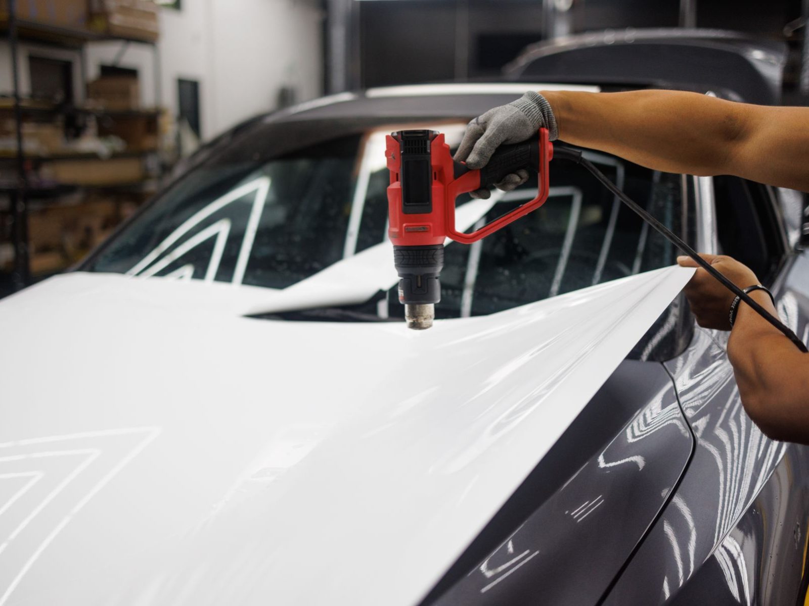 Weiße Cast-Folie wird mit der Heißluftpistole über die Motorhaube eines Autos geformt