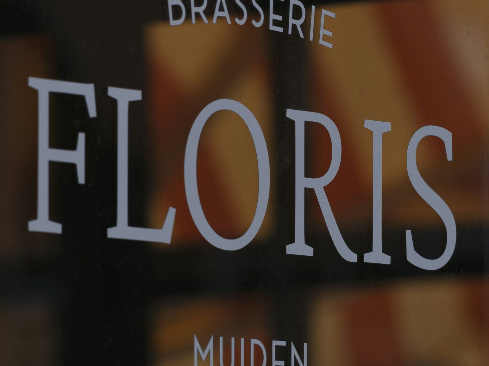 Weiße Folienbuchstaben einer Brasserie auf der Fensterscheibe