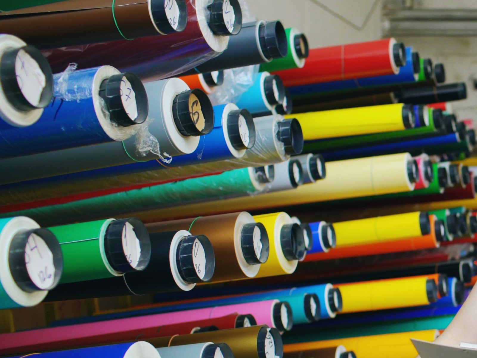 Regal voller Plotterfolien-Rollen in vielen Farben, jede Rolle mit beschrifteter Hülsenkappe