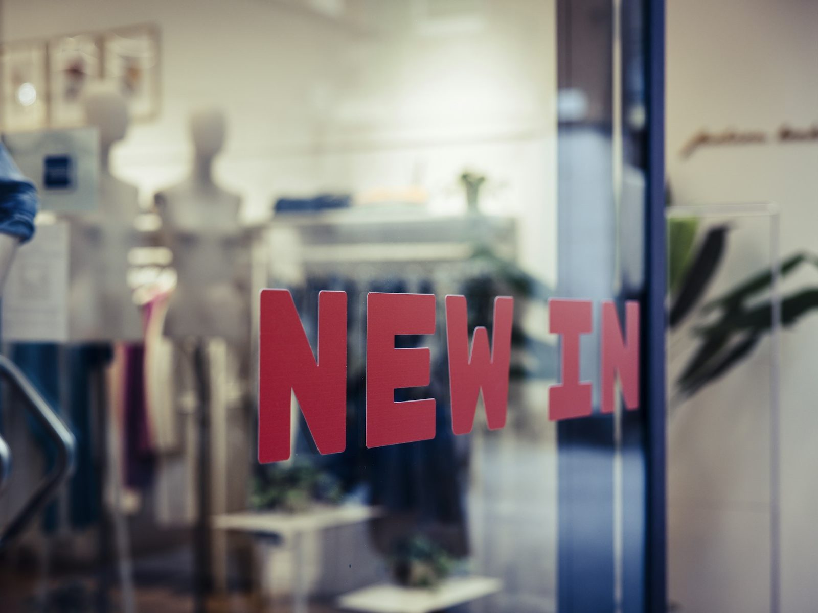 Roter Schriftzug als Folie auf einem Schaufenster, dahinter die Ware